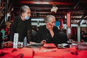 Vietnamese scholar writes calligraphy at Long Son. Calligraphy festival is a popular tradition during Tet holiday. Writing couplets for Spring Festival, new year. photo