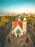 vista superior de la hermosa iglesia antigua de la ciudad de vung tau con árbol verde. pueblo del templo católico de vung tau, vietnam. foto del paisaje primaveral con puesta de sol.