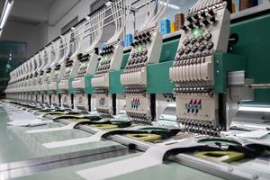 Modern and automatic high technology sewing machine for textile or clothing apparel making manufacturing process in industrial. Digital textile industry. Computerized embroidery. photo