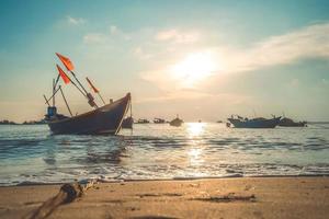 Tropical Seascape with a boat on sandy beach at cloudy sunrise or sunset. Beautiful sunset tropical beach with small boat and cinematic sky for travel and vacation in holiday relax time. photo