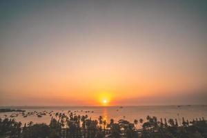 Vung Tau city aerial view with beautiful sunset and so many boats. Panoramic coastal Vung Tau view from above, with waves, coastline, streets, coconut trees and Tao Phung mountain in Vietnam. photo