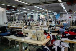 Ba Ria, VIETNAM - MAR 18 2022 Textile cloth factory working process tailoring workers equipment. This is a sewing machine factory production empty worker. photo