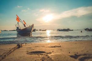 Tropical Seascape with a boat on sandy beach at cloudy sunrise or sunset. Beautiful sunset tropical beach with small boat and cinematic sky for travel and vacation in holiday relax time. photo