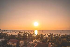 Vung Tau city aerial view with beautiful sunset and so many boats. Panoramic coastal Vung Tau view from above, with waves, coastline, streets, coconut trees and Tao Phung mountain in Vietnam. photo