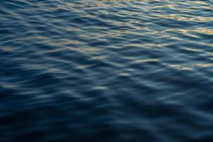 Sunset water reflect ripples at sun light. Abstract golden reflection on water sunset photo