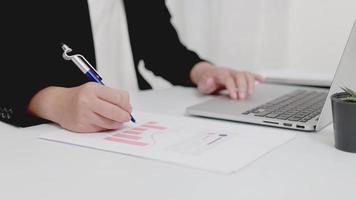 Close-up of businesswoman or accountant holding pen working with document and laptop computer on the table, Accounting financial business report to analyze and plan investment financial data. video