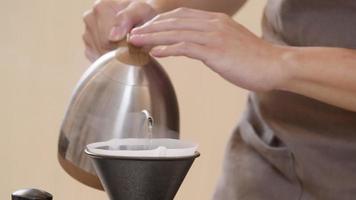 un barista professionnel verse de l'eau sur le marc de café dans le filtre comme un processus manuel. cu shot, vidéo au ralenti 4k la séquence soumise est un arrangement de prise de vue groupée