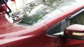 Mann wäscht Auto mit Shampoo und Wasser - sauberes Konzept für Menschen zu Hause