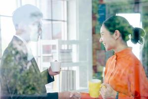 Two business people shaking hands on coffee break, view through window photo