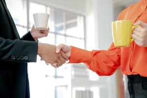 Business people shaking hands while having a cup of coffee photo