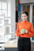 Portrait of confident businesswoman in office holding a coffee cup. photo