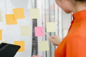 Businesswoman writing on colorful sticky note paper in business office photo