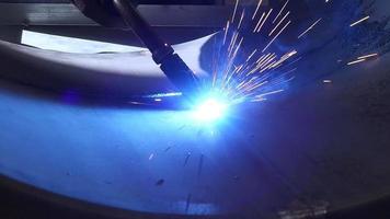 Close up view of factory worker in protective mask welding metal material with torch sparks flying around flame video