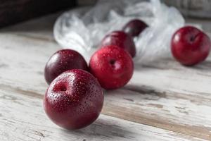 group of ripe plums on white rustic table photo