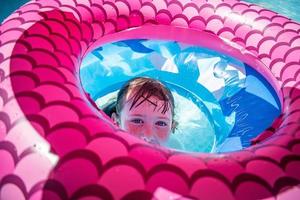 young girl hiding in center of colorful floats in pool photo