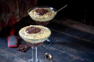 budín de vainilla y chocolate en vaso alto con trozos de chocolate rallado foto