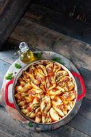 manicotti pasta shells with spinach, ricotta, mozzarella cheese in tomato sauce in red pan in rustic setting flat lay photo