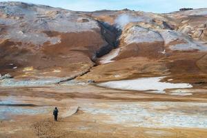 turista caminando por el paisaje del área geotérmica del noreste de islandia. foto