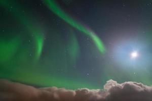 la aurora boreal sobre el cielo contra la luz de la luna llena en islandia. foto