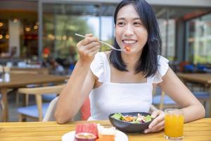 Woman eating Breakfast. Fruits such as watermelon, papaya, melon, passion fruit, orange juice and coffee. placed on a gray placemat photo