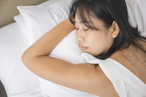 Young asian woman sleeping in bed at bedroom. she is lying on side and relax with eyes closed photo