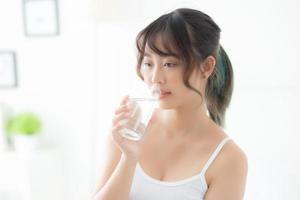 Beautiful portrait young asian woman caucasian smiling with nutrition thirsty and drinking glass of water mineral with fresh and happy, asia girl diet for healthy care and wellness, lifestyle concept. photo