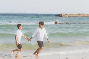 Homosexual portrait young asian couple running with cheerful together on beach in summer, asia gay going tourism for leisure and relax with happiness in vacation at sea, LGBT legal concept. photo