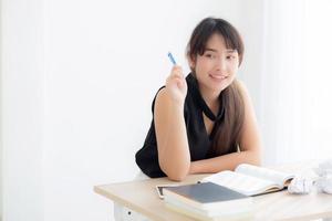 hermosa escritora asiática sonriendo pensando idea escribiendo en un diario de cuaderno con planificación trabajando en la oficina de escritorio, estilo de vida chica asiática tiene inspiración con el éxito, la educación y el concepto de negocios. foto