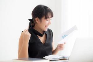 Beautiful young asian woman working laptop computer at office, businesswoman looking graph diagram analysis statistic data with excited and success, girl using notebook, business concept. photo