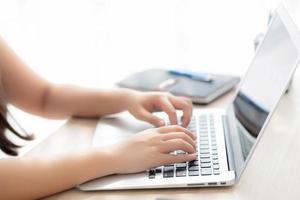 Closeup freelance asian woman working and typing on laptop computer at desk office with professional, girl using notebook checking email or social network, business and lifestyle concept. photo