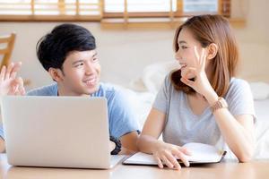 Beautiful portrait young asian couple working laptop with smile and happy sitting in bedroom, man and woman using notebook computer with excited and satisfied, business and success concept. photo