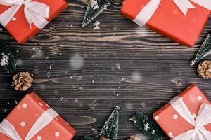 composición navideña con caja de regalo roja y decoración de etiquetas sobre fondo de madera, año nuevo y navidad o aniversario con regalos sobre mesa de madera en temporada, vista superior o puesta plana. foto