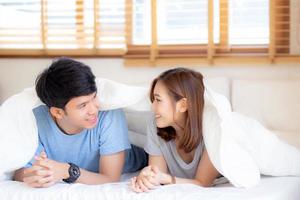 Beautiful portrait young asian couple relax and satisfied together in bedroom at home, family lying on bed confident with cheerful and happy with relationship, man and woman dating. photo