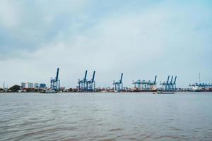 Ho Chi Minh, VIETNAM - FEB 19 2022 Transportation for export, import at Cat Lai port on Sai Gon river, crane load container to boat, this harbor is big industry service for trade photo