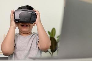 niño asiático con anteojos vr estudiando ciencias en casa, estudiante curioso usa un auricular de realidad virtual para estudiar ciencia en casa estudio en línea aprendizaje de estilo de vida futurista foto