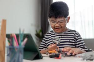 Young asia student remotely learn online at home  in coding robot car and electronic board cable in STEM, STEAM, mathematics engineer science technology computer code in robotics for kids. photo