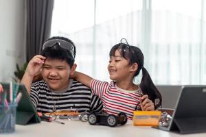 two Asian children having fun learning coding together, learning remotely at home, STEM science, homeschooling education, fun social distancing, isolation, new normal concept photo