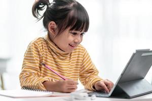 niño autoaislado usando tableta para su tarea, niño usando tableta digital buscando información en Internet durante el bloqueo de covid 19, educación en el hogar, distancia social, educación en línea de aprendizaje electrónico foto