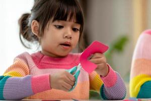 Portrait of a little asian girl cutting a paper in activities on DIY class at School.Scissors cut paper. photo