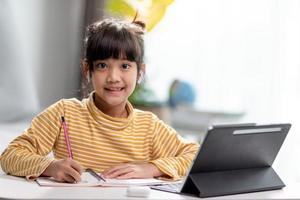 Kid self isolation using tablet for his homework,Child doing using digital tablet searching information on internet during covid 19 lock down,Home schooling,Social Distance,E-learning online education photo