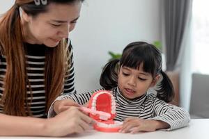 Mother teaches her child daughter accurately brushing teeth photo