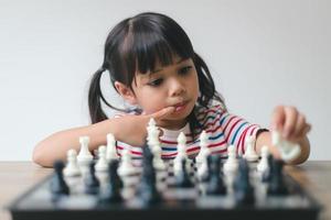 Asian little girl playing chess at home.a game of chess photo