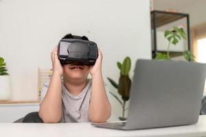 Asian Little boy with VR glasses studying sciences at home,curious student wears a virtual reality headset to study science home online study futuristic lifestyle learning photo