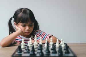 Asian little girl playing chess at home.a game of chess photo