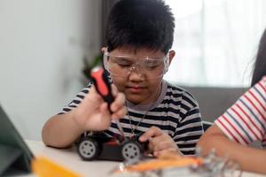 Young asia student remotely learn online at home  in coding robot car and electronic board cable in STEM, STEAM, mathematics engineer science technology computer code in robotics for kids. photo