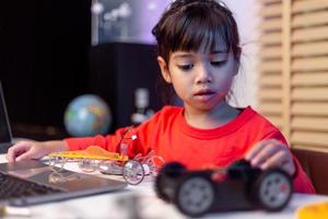 Asia students learn at home in coding robot cars and electronic board cables in STEM, STEAM, mathematics engineering science technology computer code in robotics for kids concept. photo