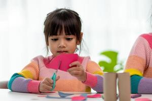 Portrait of a little asian girl cutting a paper in activities on DIY class at School.Scissors cut paper. photo