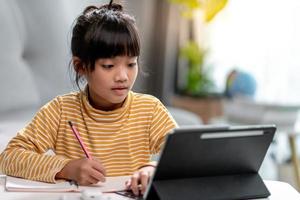 Kid self isolation using tablet for his homework,Child doing using digital tablet searching information on internet during covid 19 lock down,Home schooling,Social Distance,E-learning online education photo