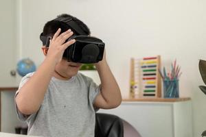 Asian Little boy with VR glasses studying sciences at home,curious student wears a virtual reality headset to study science home online study futuristic lifestyle learning photo