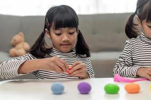 The little girl is learning to use colorful play dough in a well lit room photo